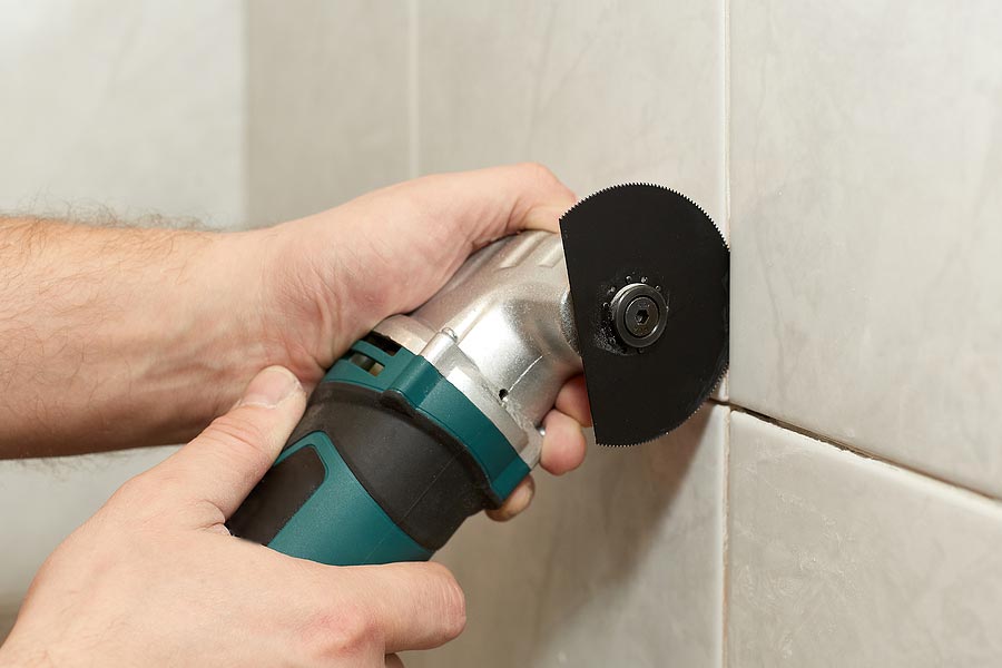 man using tool to clear out old grout